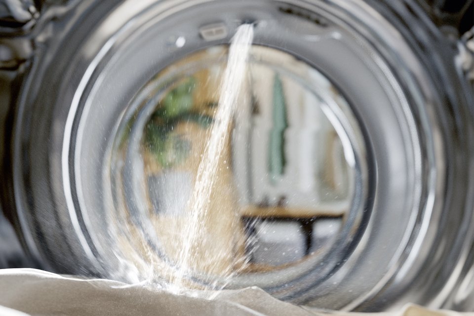 The inside of a Miele washing machine, with water being poured over a white fabric.